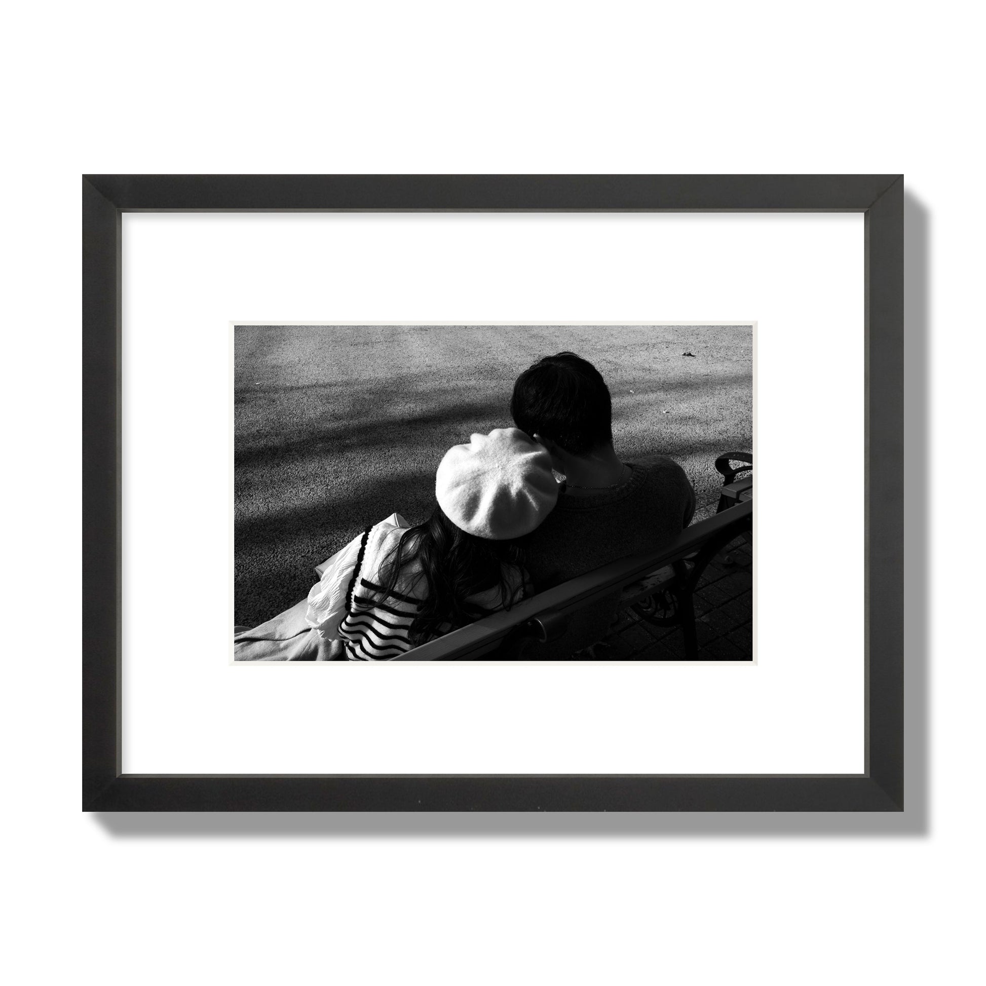 Fine art black and white street photograph of a romantic couple cuddling on a park bench. Archival pigment print, small size, black frame.