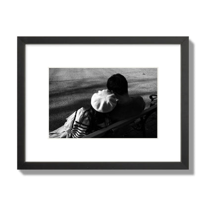 Fine art black and white street photograph of a romantic couple cuddling on a park bench. Archival pigment print, small size, black frame.