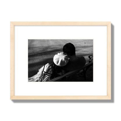 Fine art black and white street photograph of a romantic couple cuddling on a park bench. Archival pigment print, small size, natural wood frame.