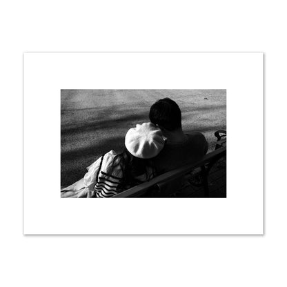 Fine art black and white street photograph of a romantic couple cuddling on a park bench. Archival pigment print, small size, print.