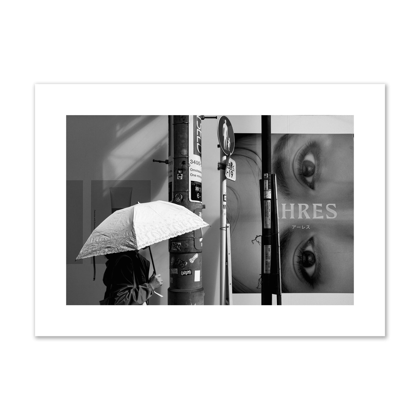 Fine art street photograph of a woman walking with an umbrella on a Tokyo street, passing beneath a billboard with two large eyes. Archival pigment print, large size, unframed.
