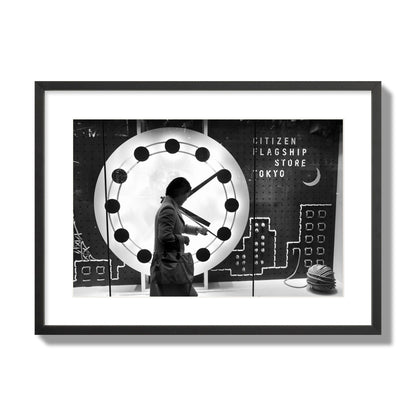 Fine art street photograph of a woman checking her watch as she walks past a giant clock on a busy Tokyo city street. Archival pigment print, large size, black frame.