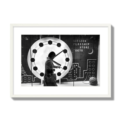 Fine art street photograph of a woman checking her watch as she walks past a giant clock on a busy Tokyo city street. Archival pigment print, large size, white frame.