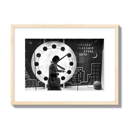 Fine art street photograph of a woman checking her watch as she walks past a giant clock on a busy Tokyo city street. Archival pigment print, medium size, natural wood frame.