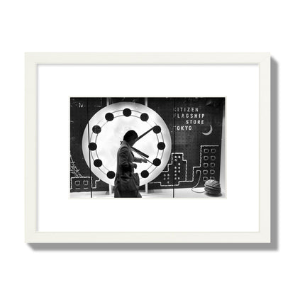Fine art street photograph of a woman checking her watch as she walks past a giant clock on a busy Tokyo city street. Archival pigment print, small size, white frame.