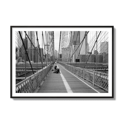 Fine art black and white photograph of a person posing on the Brooklyn Bridge with the cityscape in the background, archival pigment print, collector size, black frame