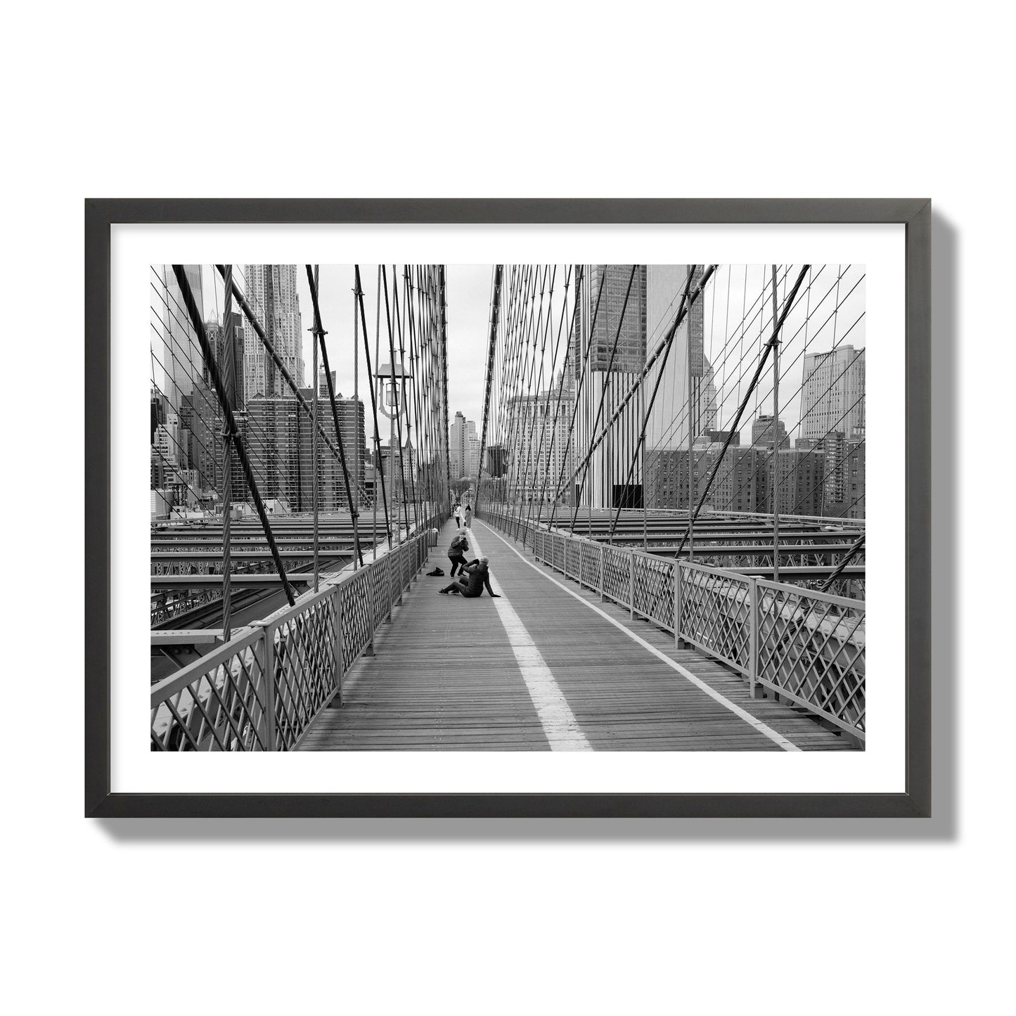Fine art black and white photograph of a person posing on the Brooklyn Bridge with the cityscape in the background, archival pigment print, giant size, black frame