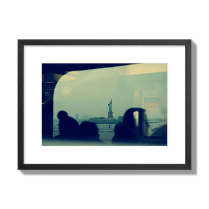 Fine art photograph of passengers silhouetted on a crowded ferry with the Statue of Liberty in the background, archival pigment print, medium size, black frame.