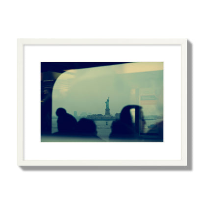 Fine art photograph of passengers silhouetted on a crowded ferry with the Statue of Liberty in the background, archival pigment print, medium size, white frame.