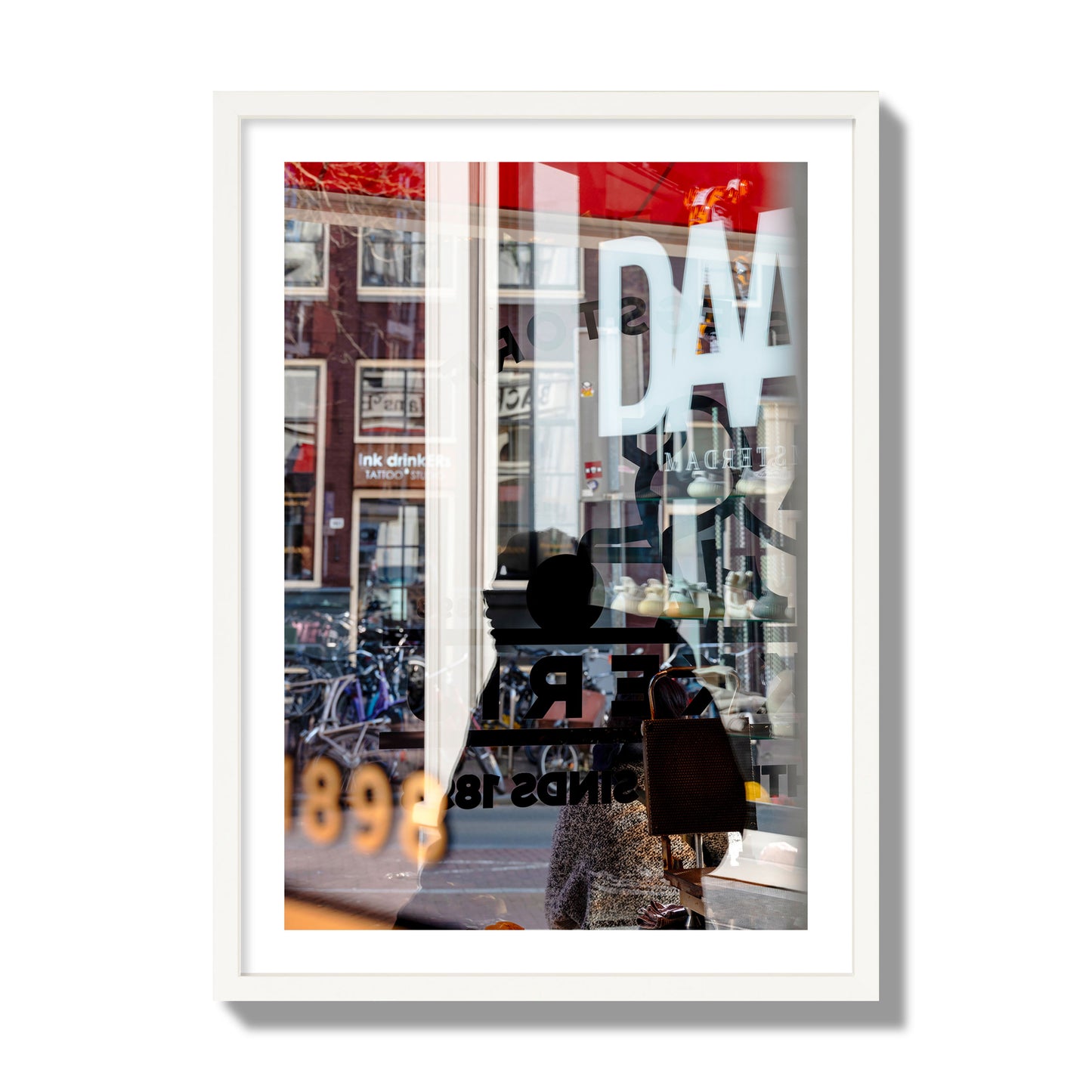 Fine art street photograph of a busy Amsterdam street scene with reflections, silhouettes, shoppers, and store signs. Archival pigment print, giant size, white frame.
