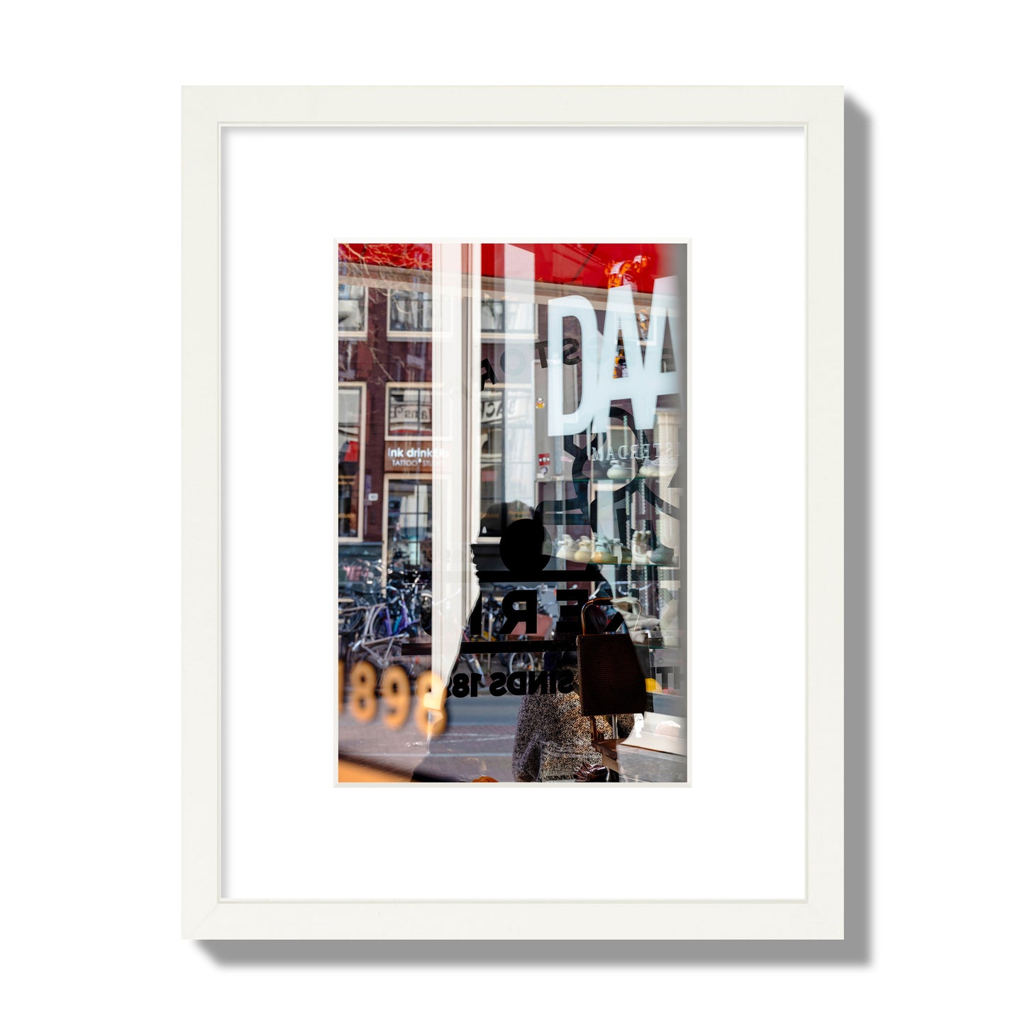 Fine art street photograph of a busy Amsterdam street scene with reflections, silhouettes, shoppers, and store signs. Archival pigment print, small size, white frame.
