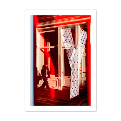 Fine art street photograph of an Amsterdam street scene showing bright red and white reflections of a large letter Y, a man walking, and multiple store fronts. Archival pigment print, collector size, unframed.