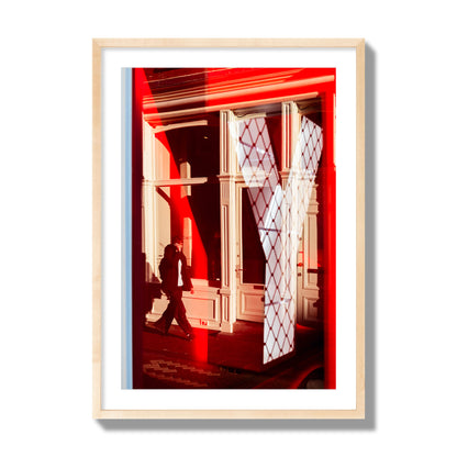 Fine art street photograph of an Amsterdam street scene showing bright red and white reflections of a large letter Y, a man walking, and multiple store fronts. Archival pigment print, giant size, natural wood frame.