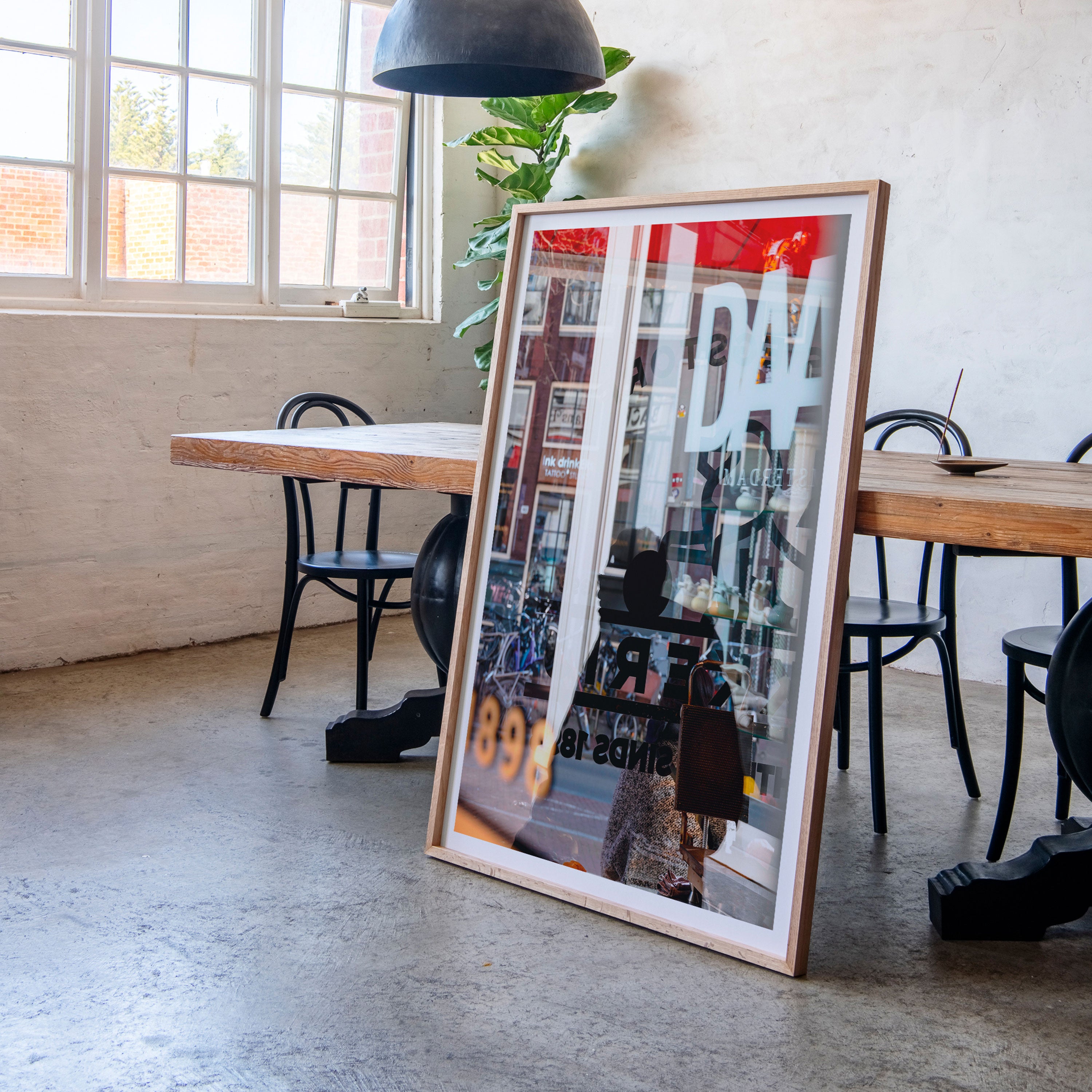 A framed fine art photograph of a busy Amsterdam street scene rest against a dining room table.