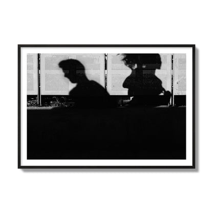 Fine art black and white street photography capturing the silhouettes of two individuals against a wall in Athens Greece, archival pigment print, collector size, black frame