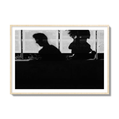 Fine art black and white street photography capturing the silhouettes of two individuals against a wall in Athens Greece, archival pigment print, collector size, natural wood frame
