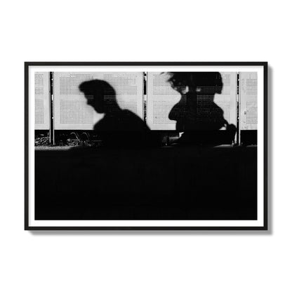 Fine art black and white street photography capturing the silhouettes of two individuals against a wall in Athens Greece, archival pigment print, gallery size, black frame