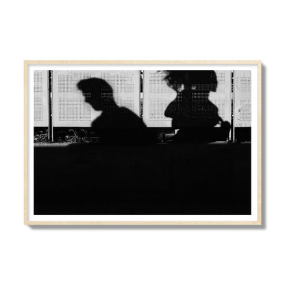 Fine art black and white street photography capturing the silhouettes of two individuals against a wall in Athens Greece, archival pigment print, gallery size, natural wood frame