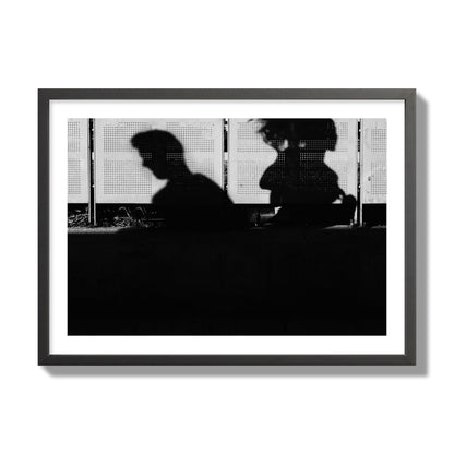 Fine art black and white street photography capturing the silhouettes of two individuals against a wall in Athens Greece, archival pigment print, giant size, black frame