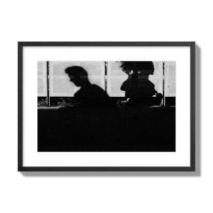 Fine art black and white street photography capturing the silhouettes of two individuals against a wall in Athens Greece, archival pigment print, large size, black frame