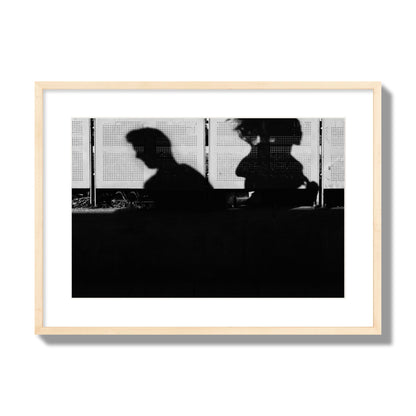 Fine art black and white street photography capturing the silhouettes of two individuals against a wall in Athens Greece, archival pigment print, large size, natural wood frame