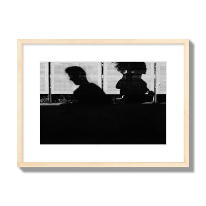 Fine art black and white street photography capturing the silhouettes of two individuals against a wall in Athens Greece, archival pigment print, medium size, natural wood frame