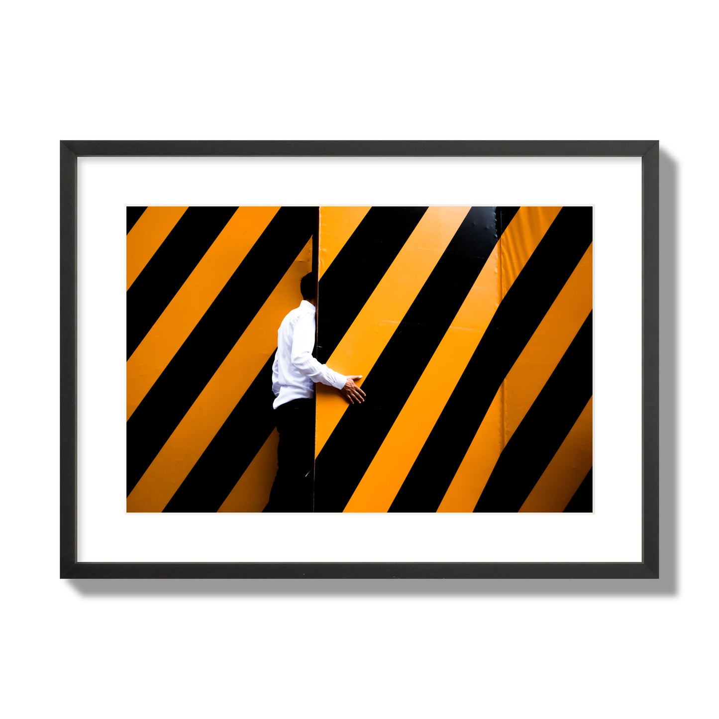 Fine art street photograph of a man opening an orange and black stripped construction door. Archival pigment print, large size, black frame.