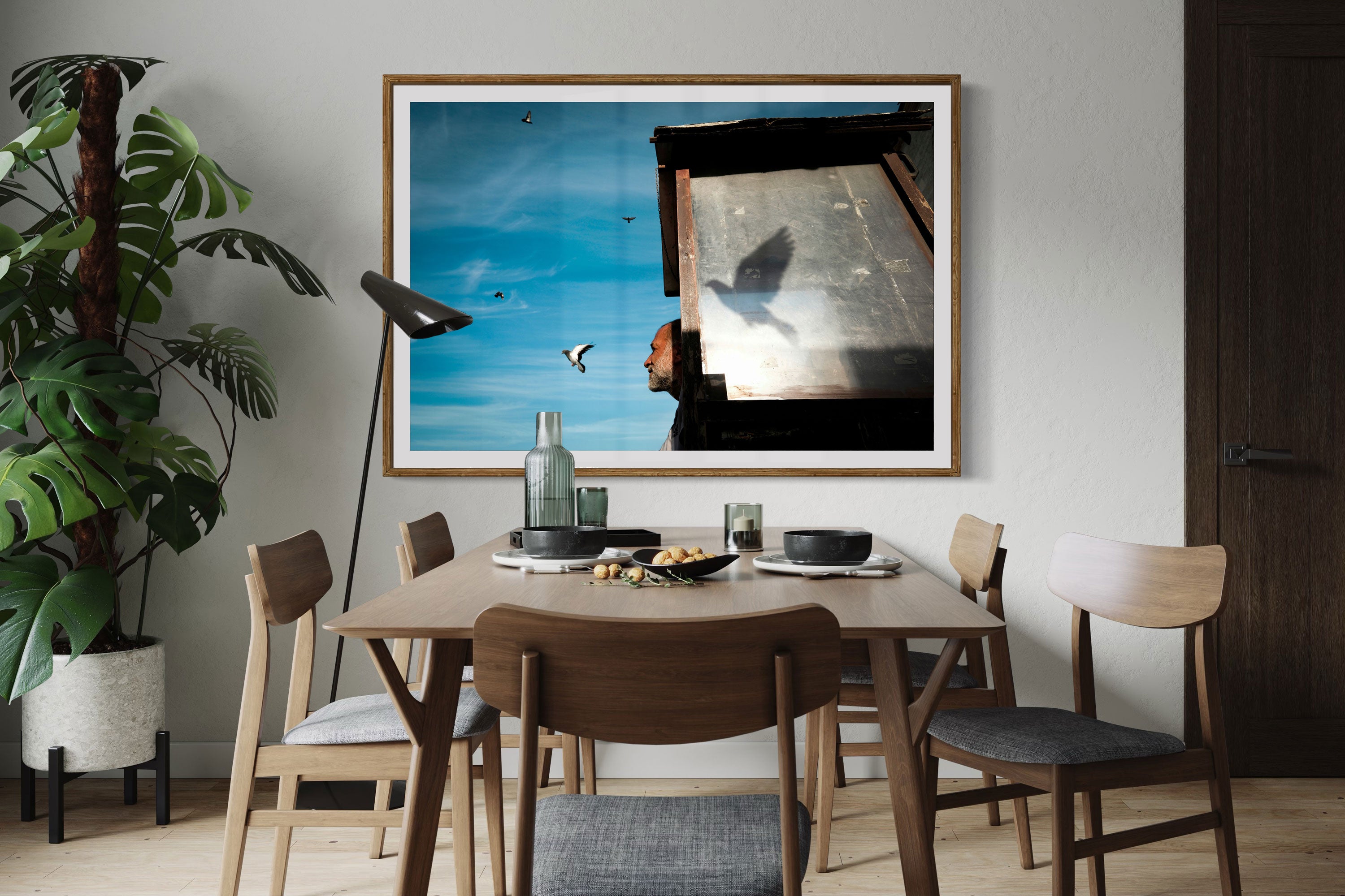 Dining room with a framed fine art street photograph of a man watching a bird fly away.