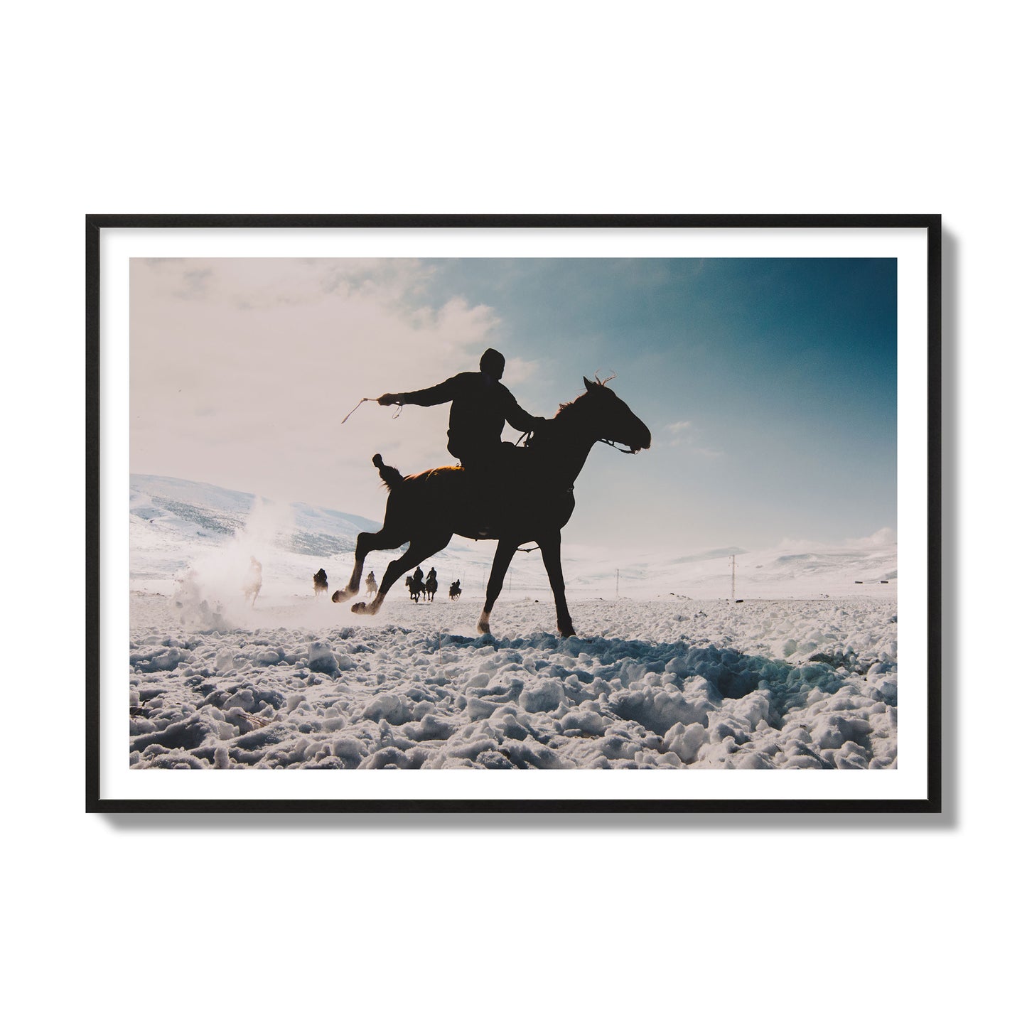 Fine art photography of a silhouetted man riding a galloping horse in a snowy field with a mountain backdrop, archival pigment print, collector size, black frame.