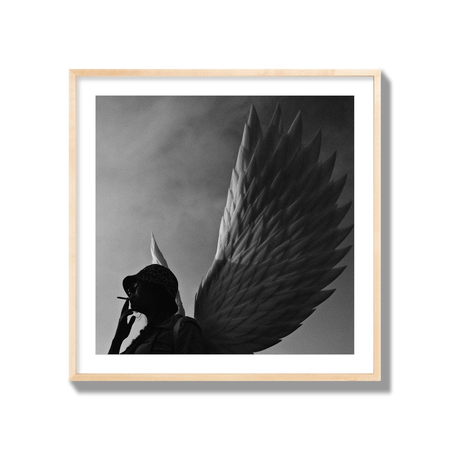 Fine art photography of a woman smoking in front of a winged statue, archival pigment print, collector size, natural wood frame.
