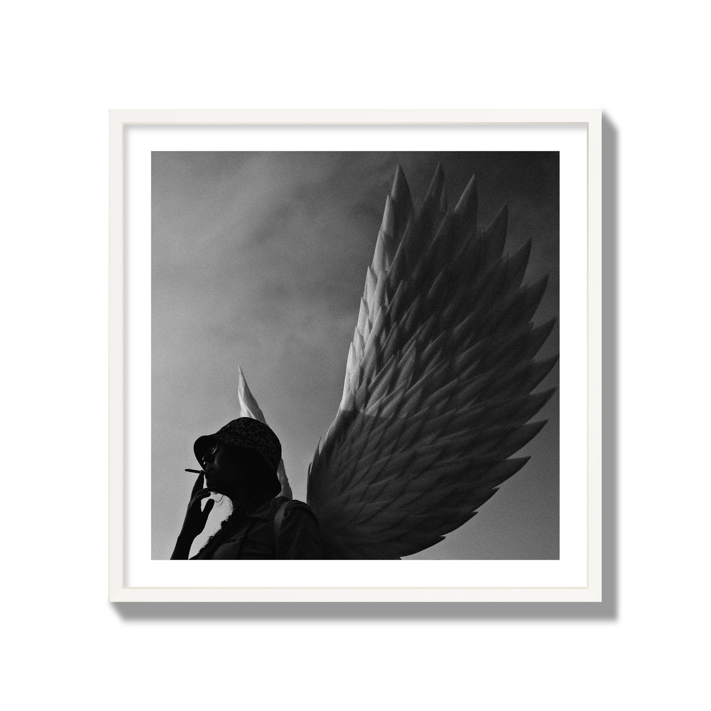 Fine art photography of a woman smoking in front of a winged statue, archival pigment print, collector size, white frame.