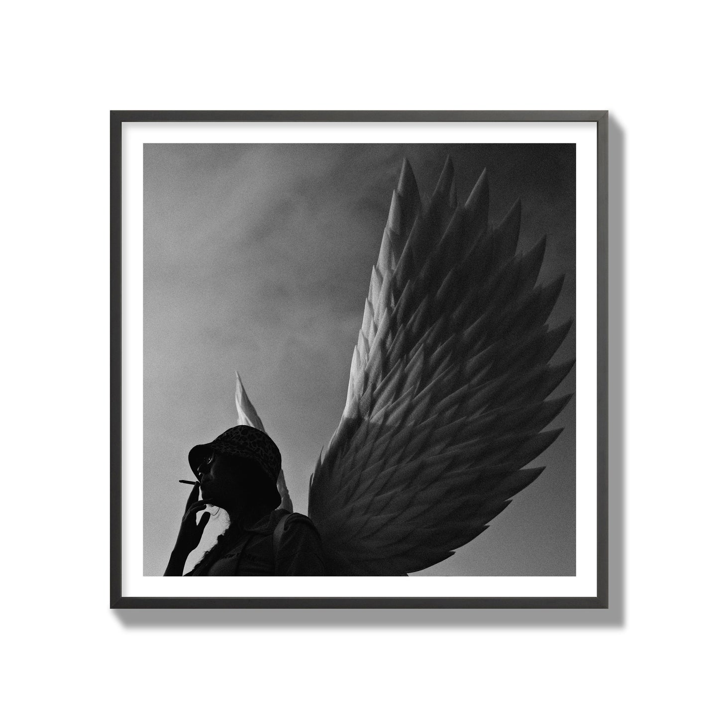 Fine art photography of a woman smoking in front of a winged statue, archival pigment print, gallery size, black frame.