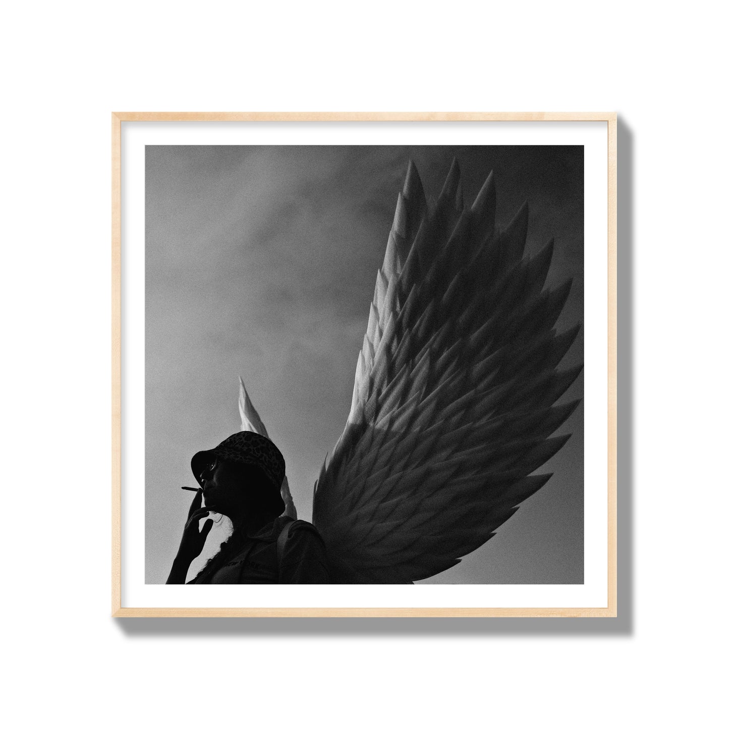 Fine art photography of a woman smoking in front of a winged statue, archival pigment print, gallery size, natural wood frame.