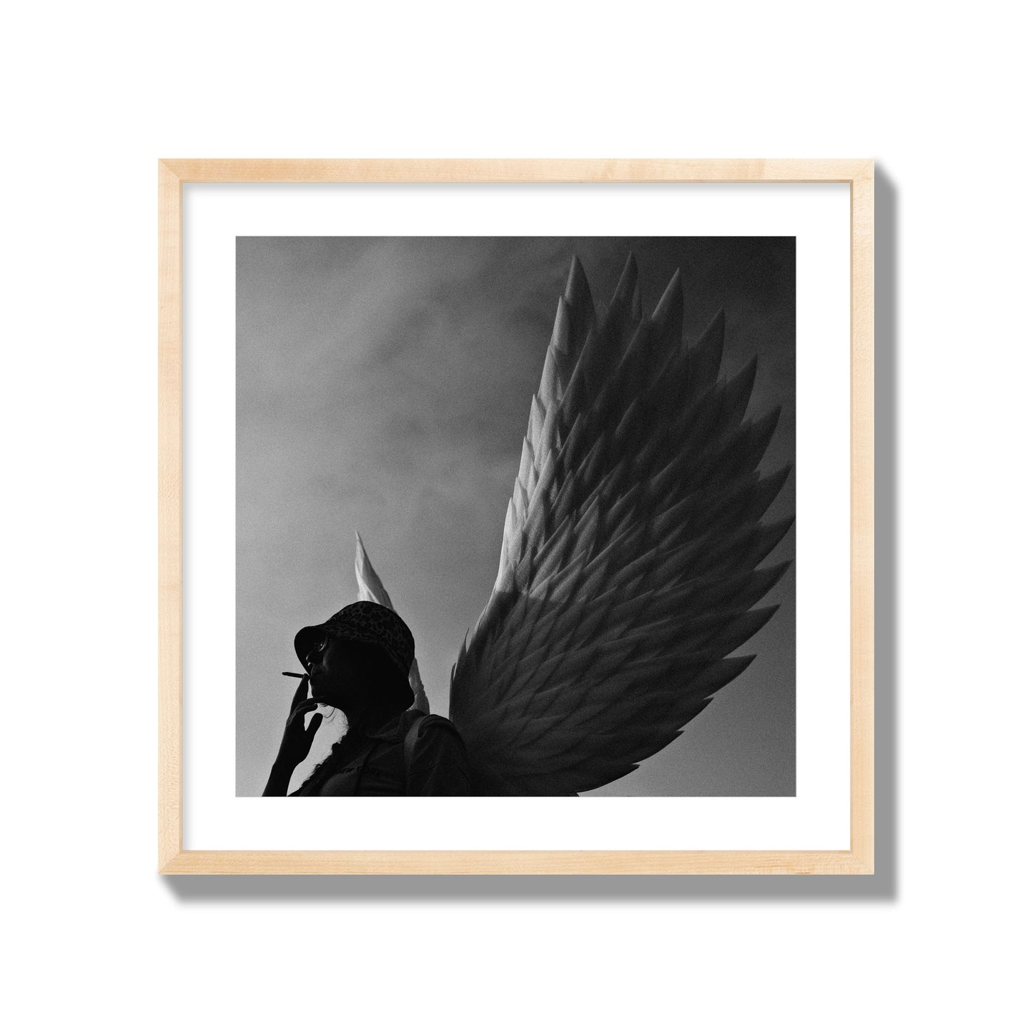 Fine art photography of a woman smoking in front of a winged statue, archival pigment print, giant size, natural wood frame.