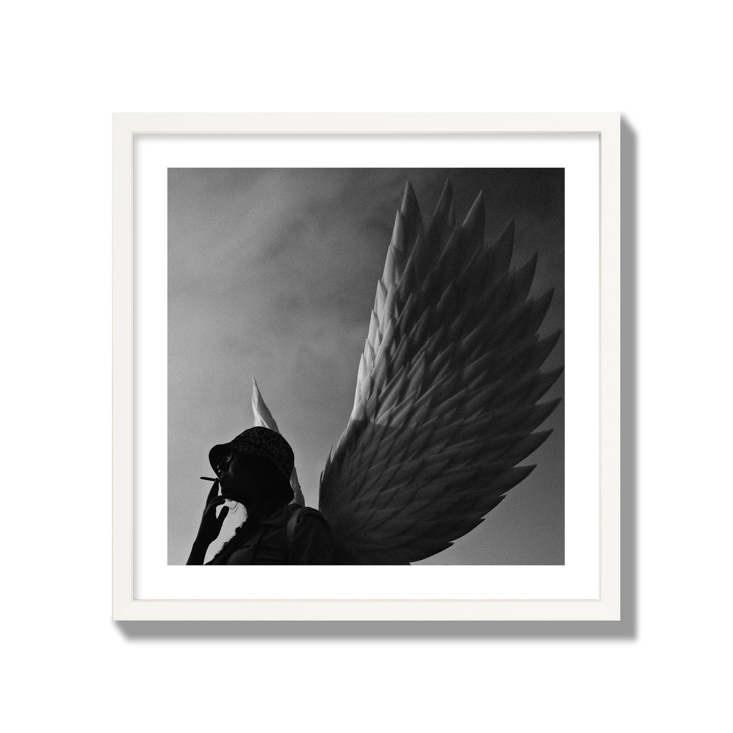 Fine art photography of a woman smoking in front of a winged statue, archival pigment print, giant size, white frame.