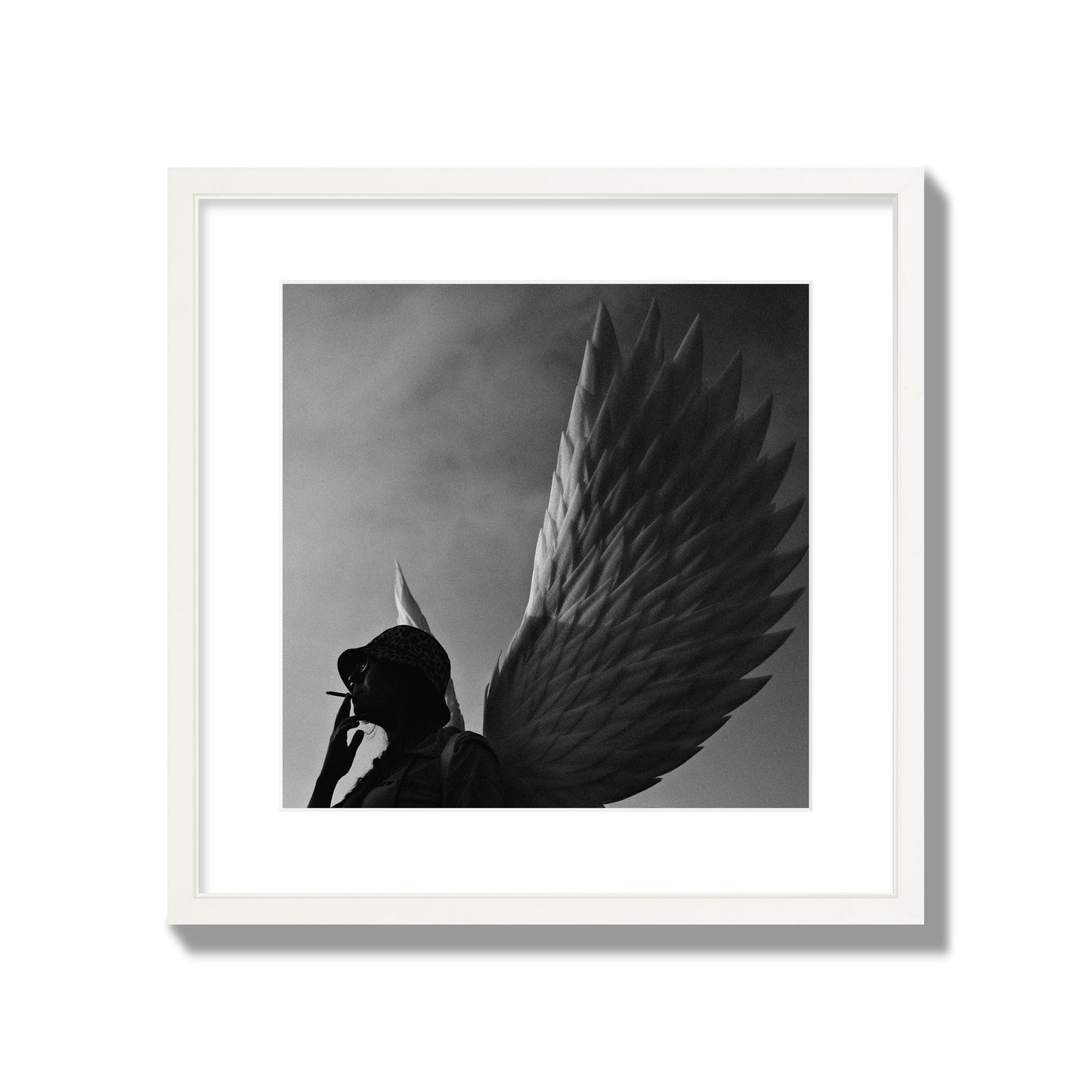 Fine art photography of a woman smoking in front of a winged statue, archival pigment print, large size, white frame.