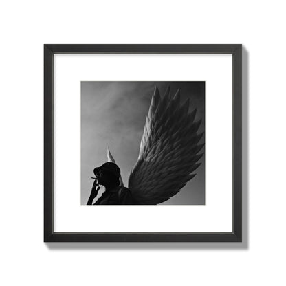 Fine art photography of a woman smoking in front of a winged statue, archival pigment print, medium size, black frame.