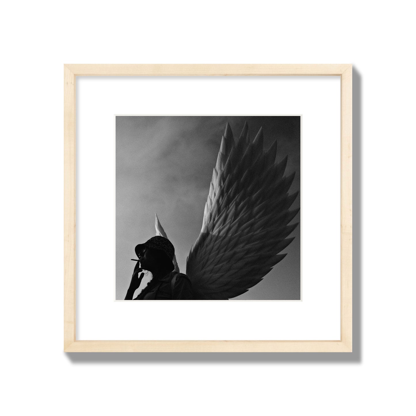 Fine art photography of a woman smoking in front of a winged statue, archival pigment print, medium size, natural wood frame.