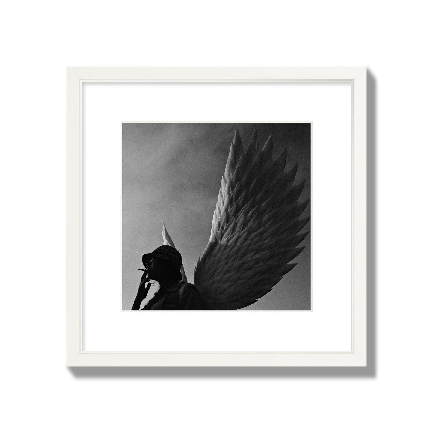 Fine art photography of a woman smoking in front of a winged statue, archival pigment print, medium size, white frame.