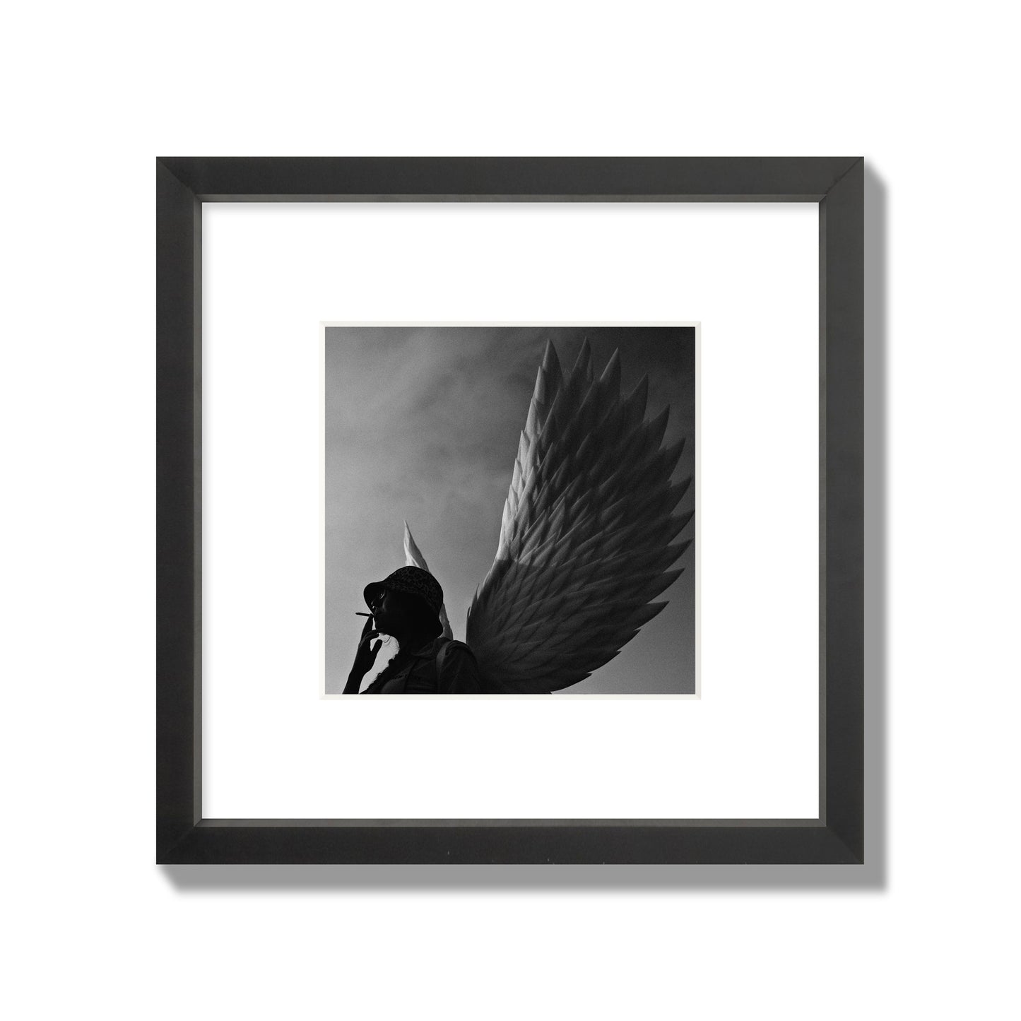 Fine art photography of a woman smoking in front of a winged statue, archival pigment print, small size, black frame.
