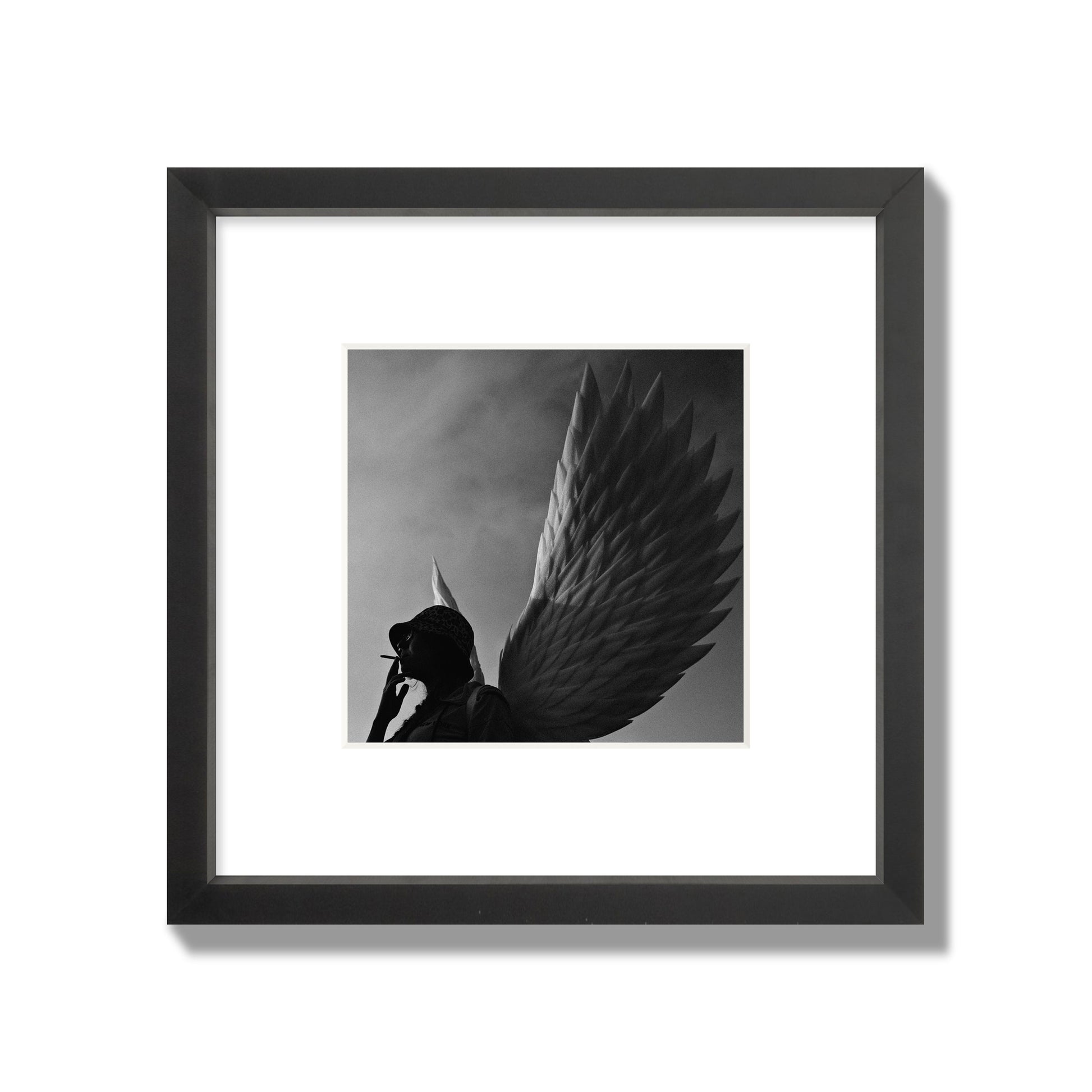 Fine art photography of a woman smoking in front of a winged statue, archival pigment print, small size, black frame.