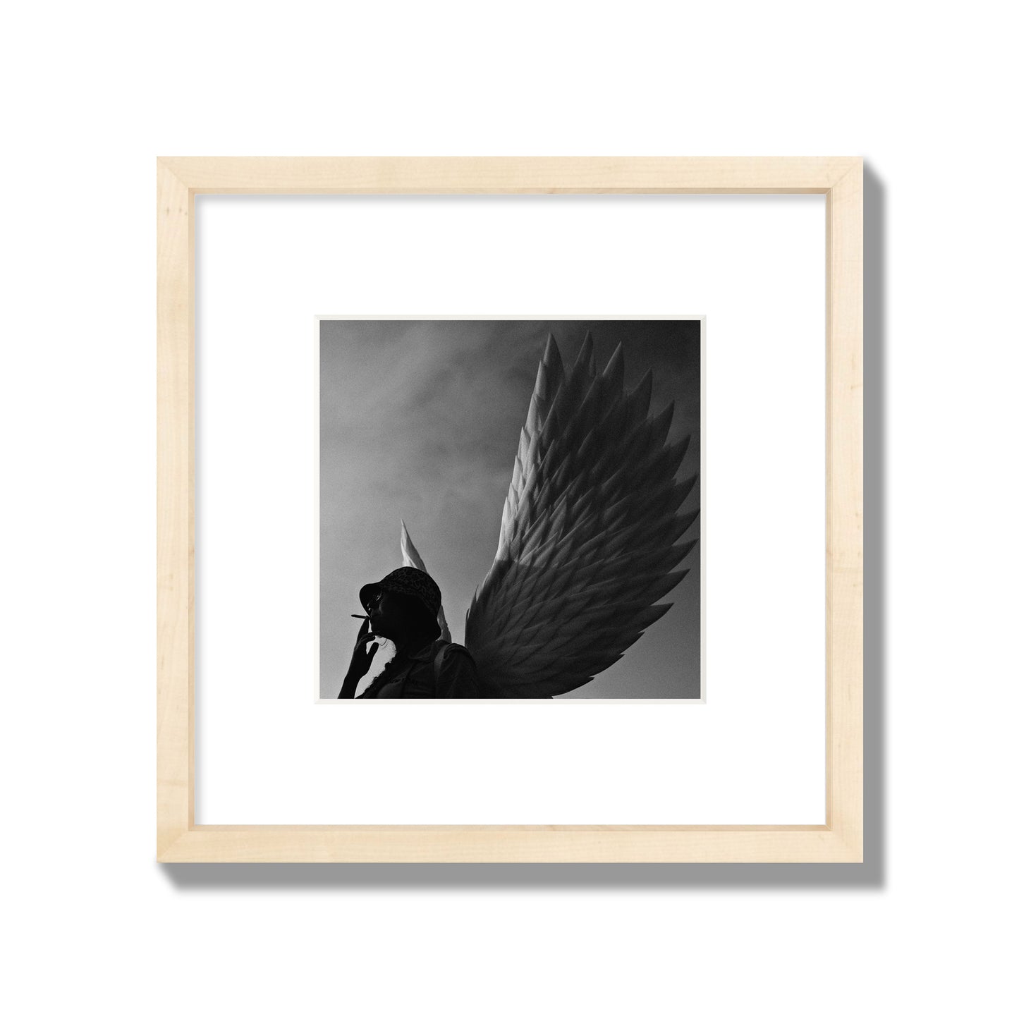 Fine art photography of a woman smoking in front of a winged statue, archival pigment print, small size, natural wood frame.