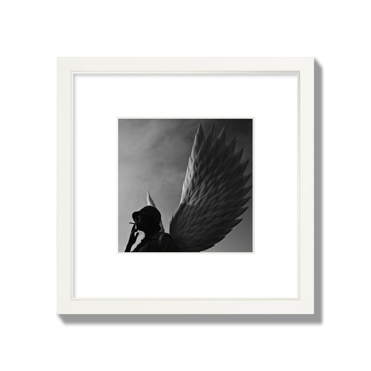 Fine art photography of a woman smoking in front of a winged statue, archival pigment print, small size, white frame.